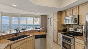 A modern kitchen with granite countertops, stainless steel appliances, and a view of the ocean. - Gulf Front Luxury Condo at Silver Beach Towers (Destin)