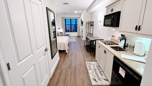Una cocina moderna con armarios blancos, un microondas y un comedor con mesa y sillas.