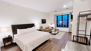 Un dormitorio moderno con una cama grande, un sofá, una mesita de centro y un ventanal con vistas.