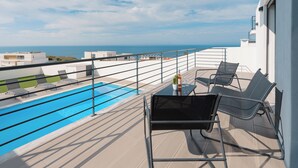 A balcony with a pool, lounge chairs, and a table with a drink. - Silver Villa with ocean view (Atalaia)