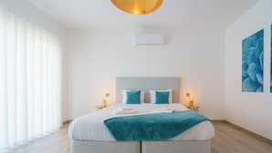 A modern bedroom with a large bed, two bedside tables with lamps, a ceiling light, and a wall-mounted air conditioner. - Silver Villa with ocean view (Atalaia)