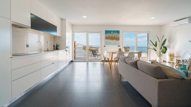 A modern kitchen with a dining area, a sofa, and a view of the sea. - Silver Villa with ocean view (Atalaia)
