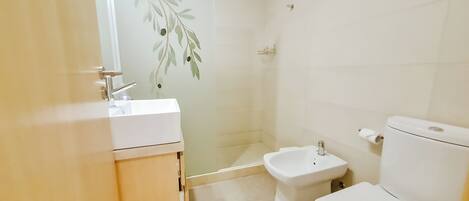 Un baño con lavamanos blanco, un bidé y un inodoro.