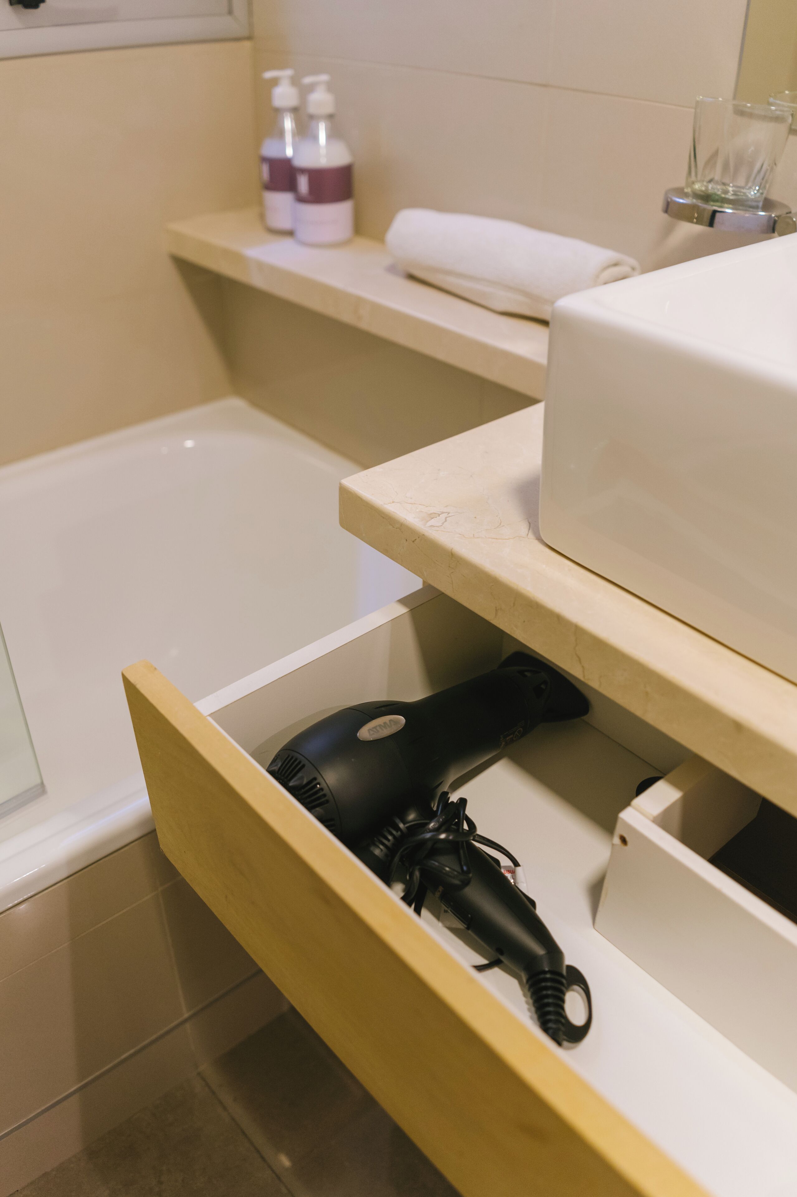 A bathroom with a bathtub, a towel rack, and a shelf with toiletries.