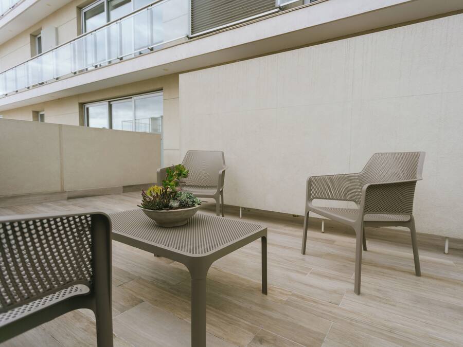 Un espacio al aire libre moderno con una mesa, dos sillas y una planta en maceta.