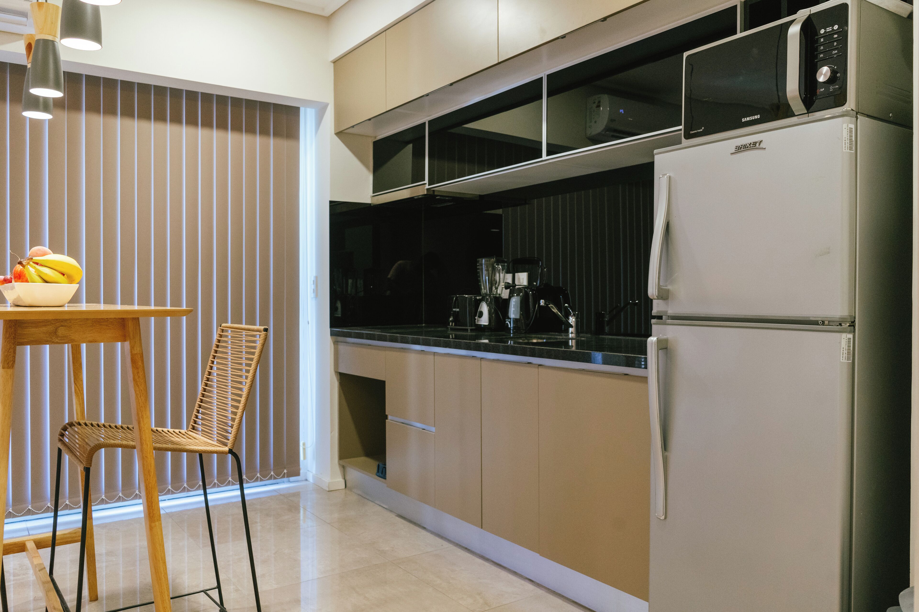 Una cocina moderna con microondas, refrigerador y comedor con mesa y silla.