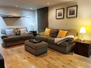 Un salon avec deux canapés, une table basse et une lampe. Deux tableaux encadrés sont accrochés au mur.