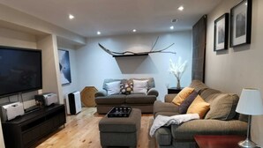 Un soggiorno moderno con una TV a schermo piatto, due divani, un tavolino da caffè e un pavimento in legno.