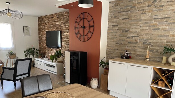 Un salón moderno con una mesa de comedor de madera, sillas de cuero negro y un gran reloj de pared.