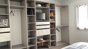 Un dormitorio amplio con un armario grande, una cama con colcha y una ventana con cortinas.