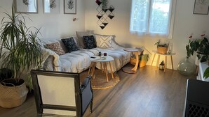 Un salón acogedor con un sofá, una silla, una mesita y una ventana con cortinas.