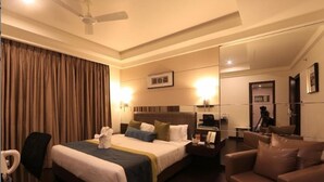 A hotel room with a large bed, a desk, a chair, and a mirror. - Hotel Regalia Tirupati (Tirupati)