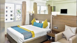 A hotel room with a large bed, a sofa, a small table, and a TV. - Hotel Regalia Tirupati (Tirupati)