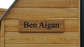 A wooden sign with the name "Ben Aigan" mounted on a building.