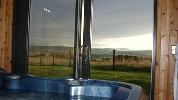 Ein Whirlpool mit Blick auf ein grasbewachsenes Feld und Hügel.