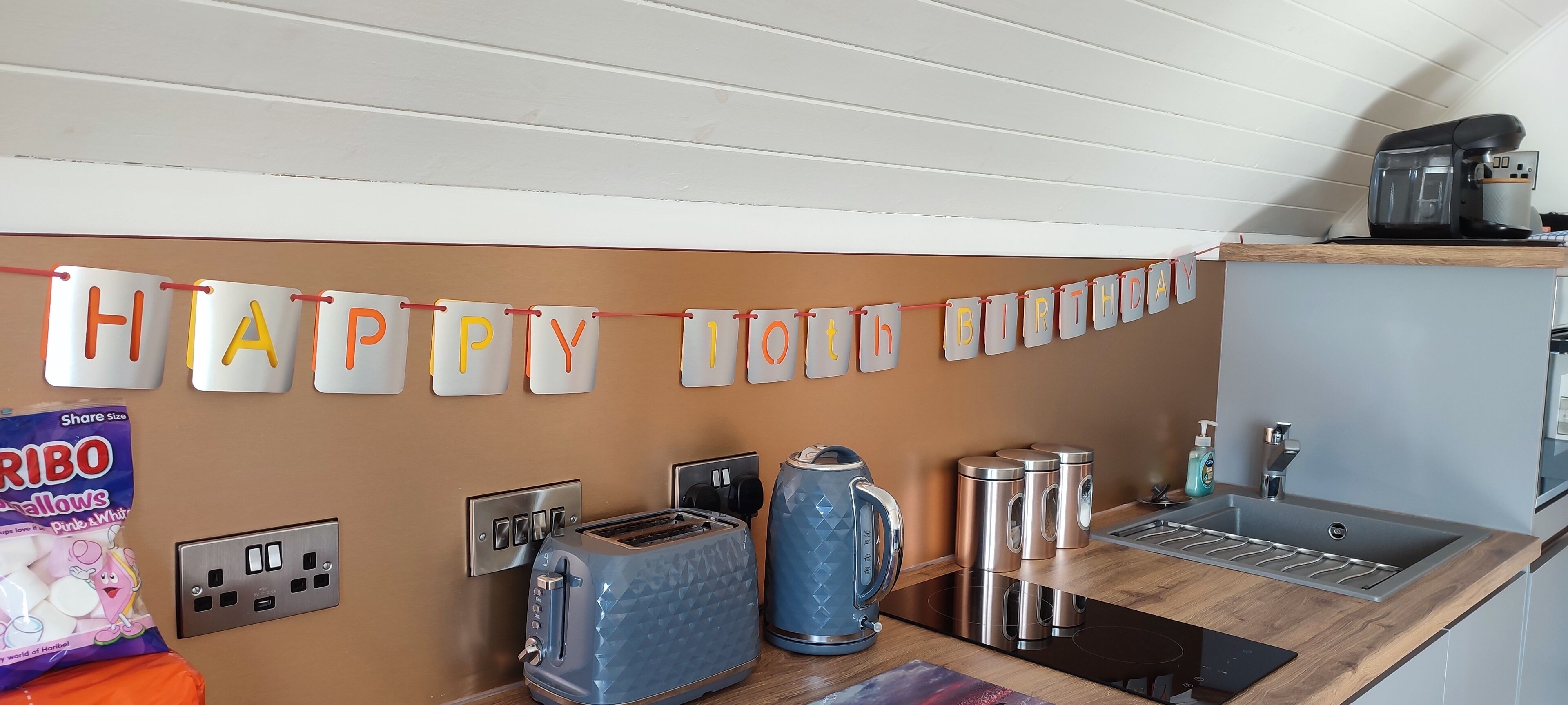 Una cucina con un festone di compleanno, un tostapane, un bollitore e una macchina per il caffè.