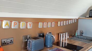Una cucina con un festone di compleanno, un tostapane, un bollitore e una macchina per il caffè.