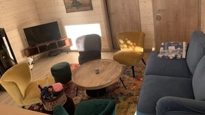 A cozy living room with a wooden ceiling, a television, a sofa, a coffee table, and a colorful rug. - Beautiful Chalet "Hygge" (venosc)
