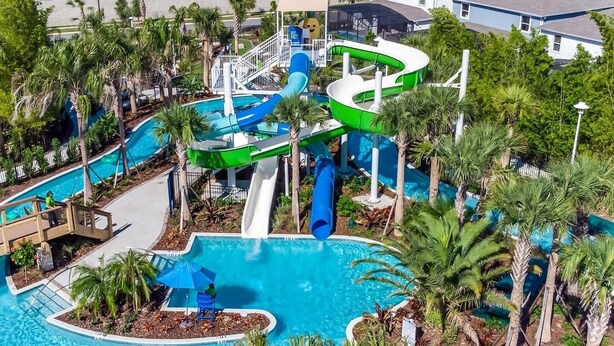 Un parque acuático con varias toboganes y una piscina central rodeada de palmeras.