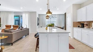 Una cocina moderna con armarios blancos, una isla central y una lámpara colgante.