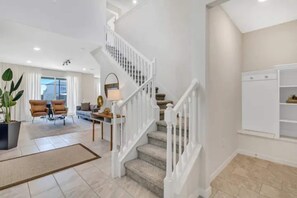 A spacious living area with a staircase, a sofa set, and a dining table.