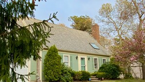 A two-story house with a green exterior, a chimney, and a small porch. - Lovely three bedroom home located in desirable Bayside neighborhood! (South Dennis)