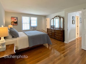 Cozy retreat with a neatly made bed, dresser, and mirror.