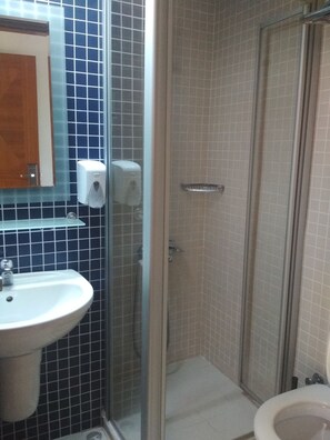 A bathroom with a sink, a glass shower enclosure, and a toilet.