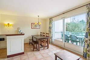 Un coin repas avec une table et des chaises, une petite cuisine avec un comptoir et un évier, et un balcon avec des chaises.