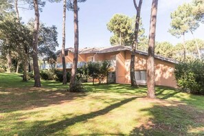 Un bâtiment à deux étages, doté d’un toit plat, entouré d’arbres et d’une pelouse bien entretenue.