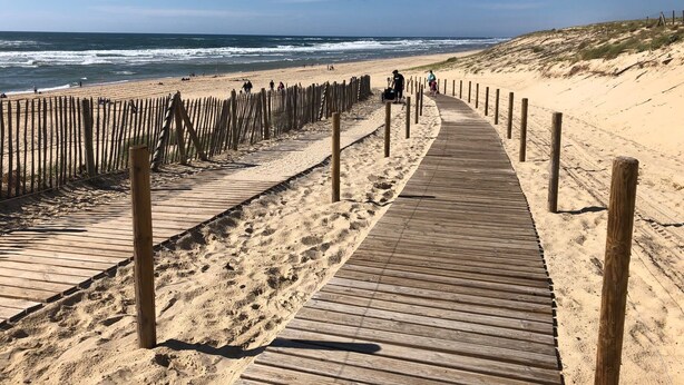 A wooden boardwalk leading to a sandy beach with ocean views.