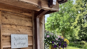 Una cabaña de madera con un letrero que dice "Nuthatch Cottage".