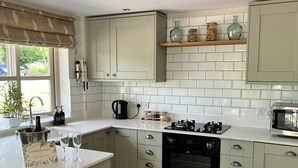 Una cocina moderna con armarios de colores claros, una isla central, horno empotrado y microondas.