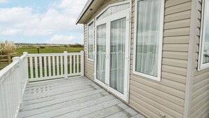 Une maison avec une terrasse, des balustrades blanches et de grandes fenêtres.