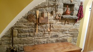 A rustic stone wall with various kitchen utensils and a wooden chest. - Comfortable house in the Pyrenees with views (Ainsa-Sobrarbe)