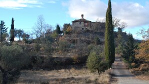 A stone building with a tiled roof, situated on a hill surrounded by trees and shrubs. - Comfortable house in the Pyrenees with views (Ainsa-Sobrarbe)