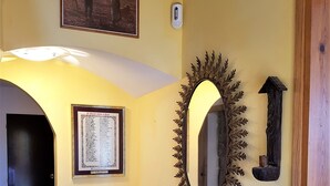 A hallway with a radiator, a wooden bench, a framed picture, a wall-mounted mirror, and a door. - Comfortable house in the Pyrenees with views (Ainsa-Sobrarbe)