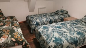 Une chambre de dortoir avec deux lits simples, chacun recouvert d’une couvre-lit à motifs floraux. Il y a deux fenêtres, une de chaque côté du mur, et un radiateur sur le mur.