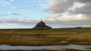 Une structure ressemblant à un château, située dans un vaste champ ouvert, sous un ciel nuageux.