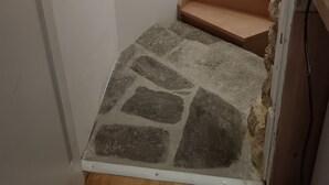 Un escalier avec un palier carrelé en pierre et des marches en bois.