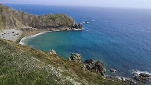 Un paysage côtier caractérisé par une côte rocheuse, des eaux turquoise et limpides, et une vue lointaine sur la mer.