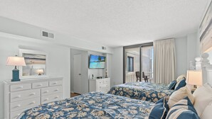 Une chambre d’hôtel avec deux lits, un bureau, une chaise et un téléviseur.