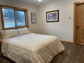 A bedroom with a bed, a window with a view of trees, and two framed pictures on the wall.