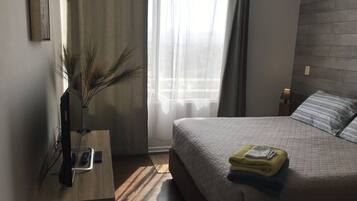 A bedroom with a bed, bedside table, lamp, and a window with curtains.