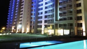 A multi-story hotel building with a swimming pool in the foreground.
