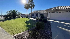 A residential area with a well-maintained lawn, a palm tree, and a house with a tiled roof. - Diamond in the Desert💎🏝HEATED/COOLED Pool and Spa NO EXTRA CHARGE (Peoria)