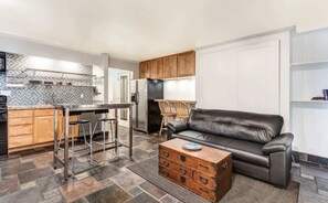 A compact living space with a kitchenette, a leather sofa, and a coffee table.
