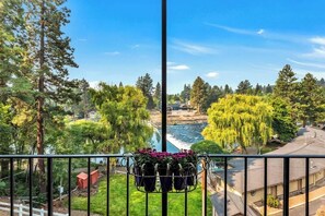 A balcony with a view of a river, trees, and a small building.