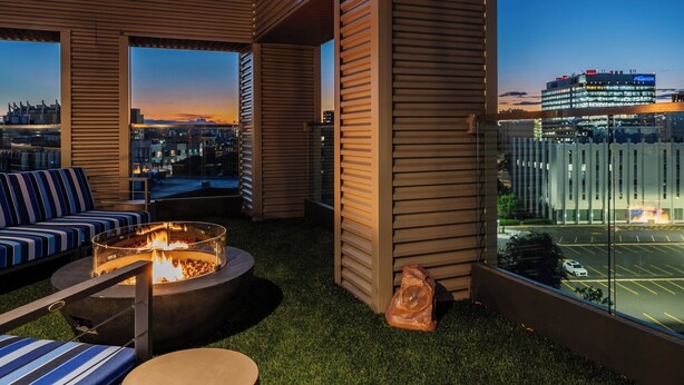 Terraza en la azotea con un brasero, zona de estar y vistas a la ciudad al atardecer.