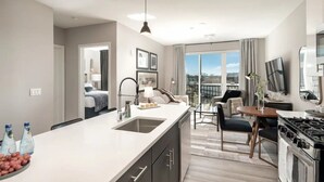 Una cocina moderna con una isla grande, un comedor con mesa y sillas, y vistas a través de amplios ventanales.